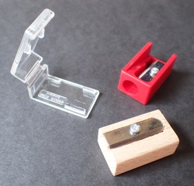 The red, plastic bodied Kum Mikro (2.9g) sharpener with its plastic shavings case (2.3g) removed, also the wooden bodied Kum Woodcutter single hole sharpener (3.5g)