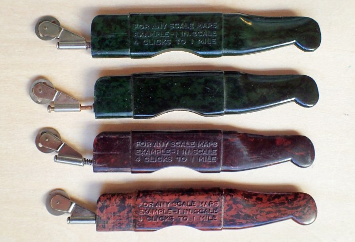 Four variants of the bakelite Velos Clicker. The development of the small wheel is apparent, as it the later inclusion of a small spring to keep the wheel steady and not swing out of position when moved along a line on a map.