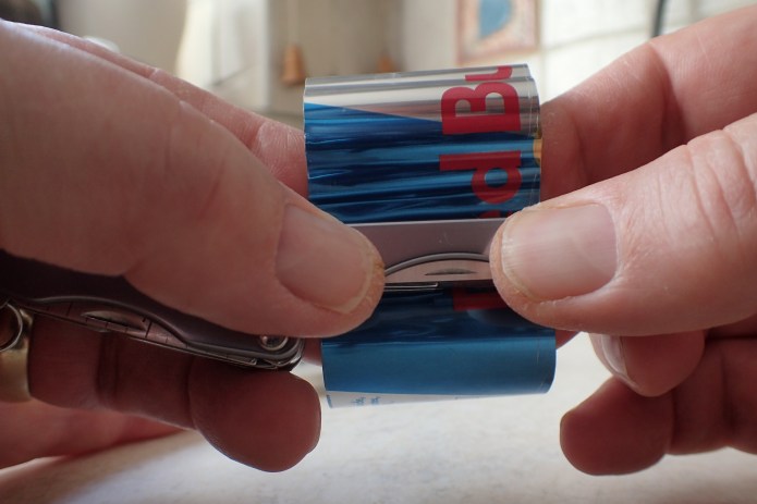 The metal tube is then rotated in the hands, and folded against my straight edge, producing a ring of creased folds around its circumference