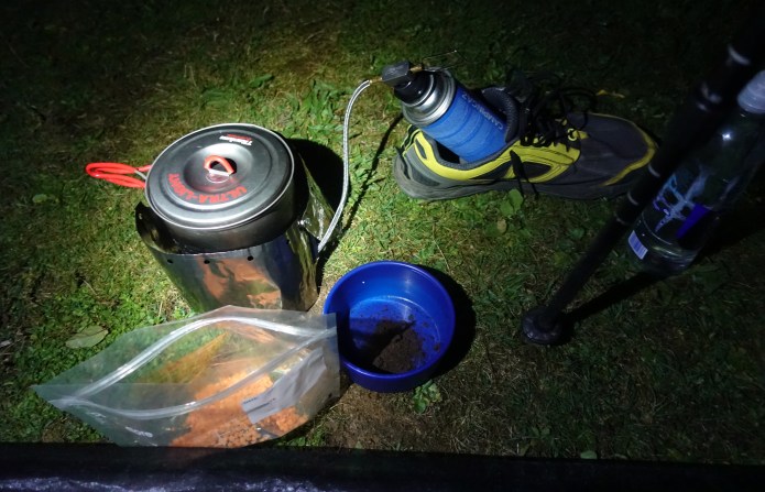 Preparing a late evening meal on trail. Canister propped up in trail shoe for stability, suppling gas supply to Kovea Spider