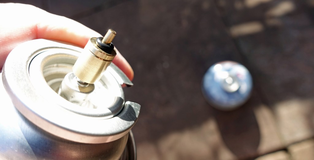 Pushed on to the bayonet of a butane gas cartridge there will be a brief venting of gas