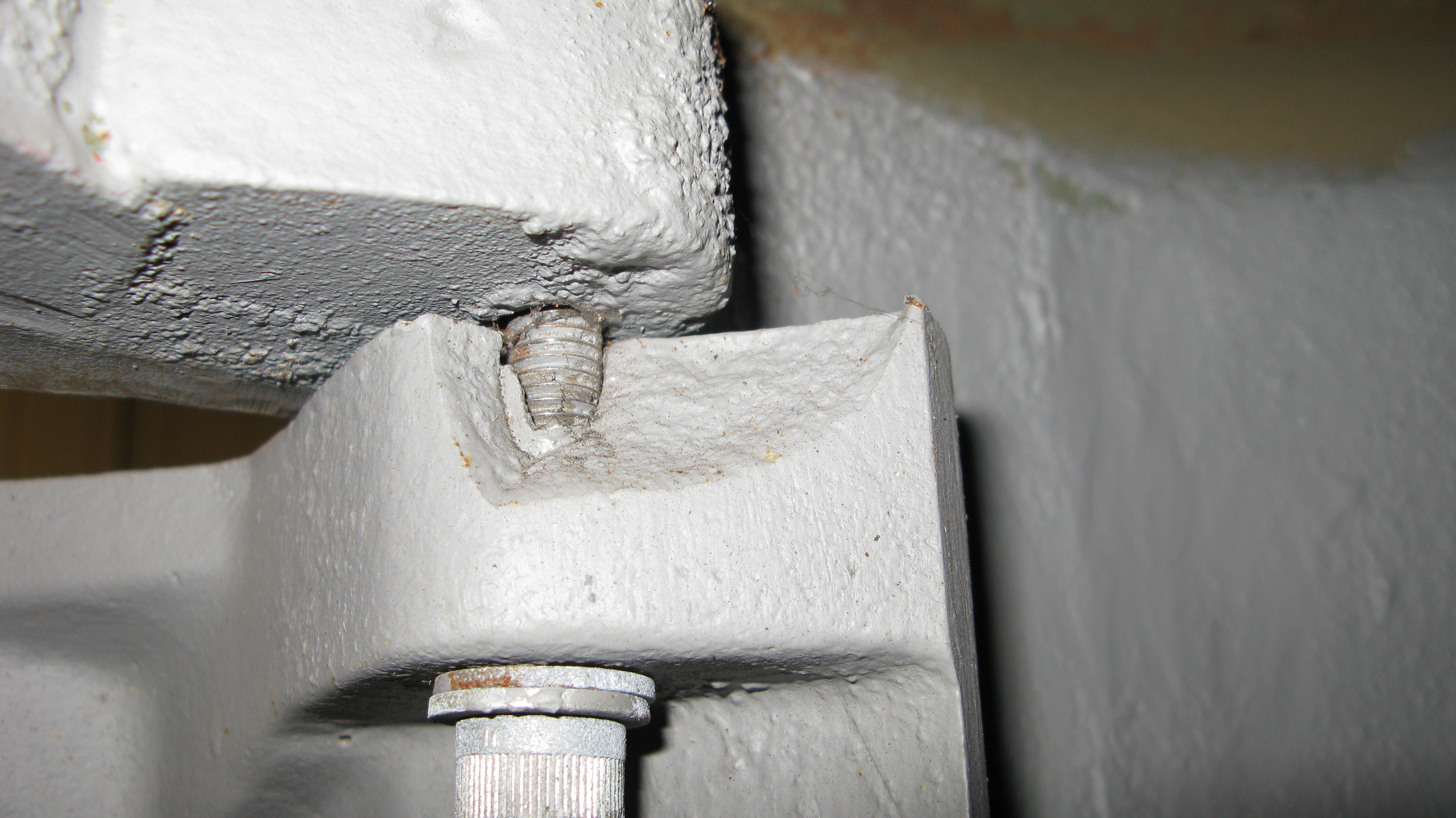 Close up of broken hinge on Nigerian pillar box. The hinges on these boxes were a poorly designed alternative. Susceptible to both screws coming adrift and thin castings breaking, this is the Achilles heel of the boxes