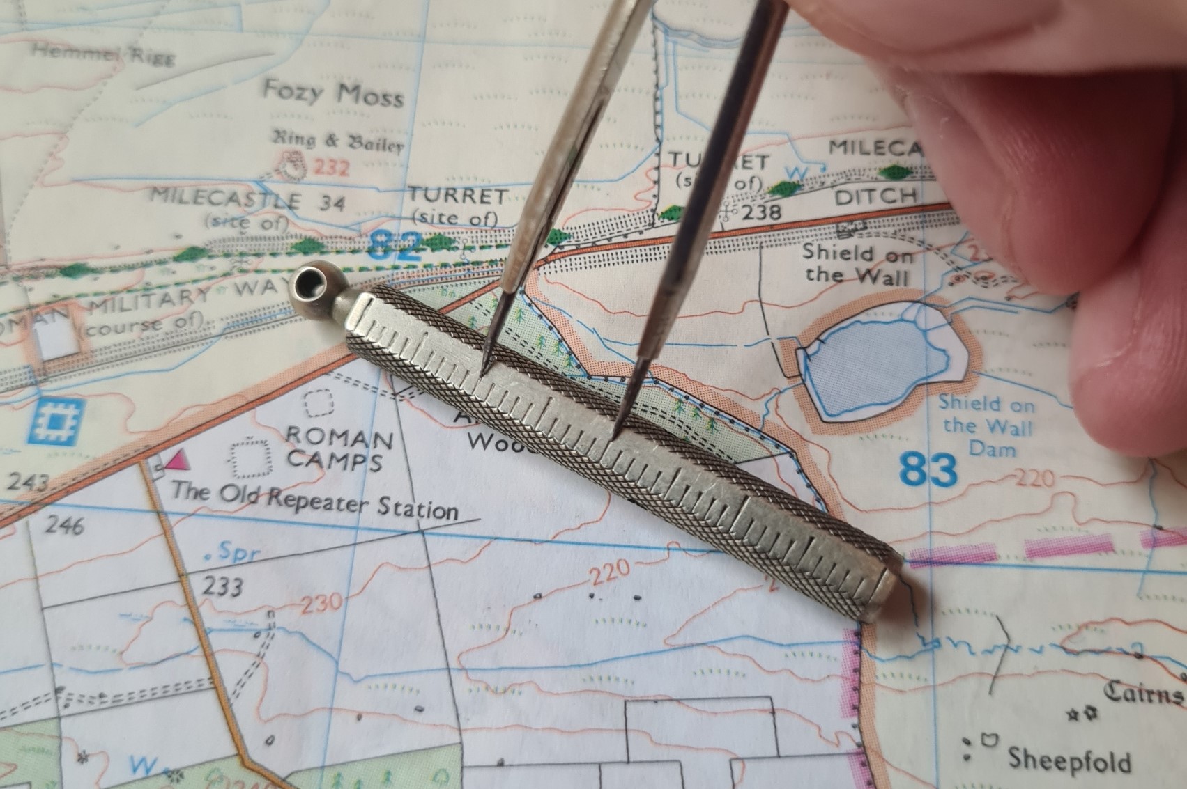 A measured distance on the map can be read off against the centimetre scale on the divider protective sheath